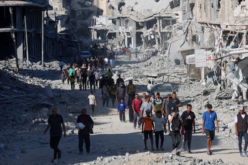 Palestinians walk past rubble following Israeli forces' withdrawal from the area, amid a ceasefire between Israel and Hamas in Gaza, in Khan Younis, in the southern Gaza Strip October 11, 2025. REUTERS/Ramadan Abed