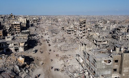 A drone view shows Palestinians walking past the rubble following Israeli forces' withdrawal from the area, amid a ceasefire between Israel and Hamas in Gaza, in Gaza City