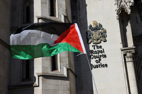 A Palestinian flag is held up outside the Royal Courts of Justice, on the day judges decide whether the co-founder of Palestine Action can challenge the UK government's ban on the group,