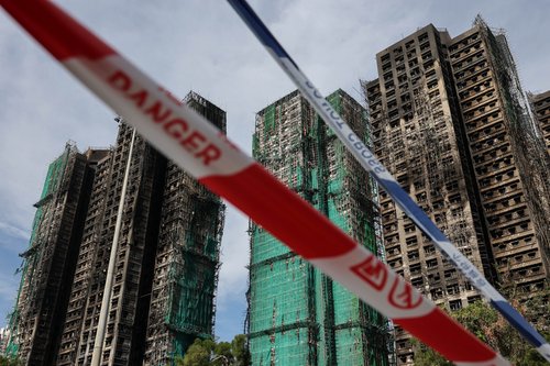 Police cordons are placed at the scene of the Wang Fuk Court housing estate fire as mourners pay tribute to the victims, in Tai Po, Hong Kong, China, November 28, 2025. REUTERS/Tyrone Siu