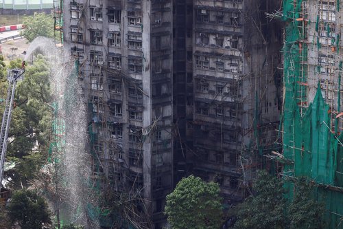 A firefighter works in front of the multiple charred buildings of Wang Fuk Court complex following a deadly fire, in Tai Po, Hong Kong, China, November 28, 2025. REUTERS/Tyrone Siu housing estate,