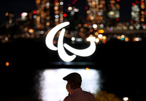 paraolimpijske igre, Visitor wearing looks at illuminated Paralympic symbol in Tokyo