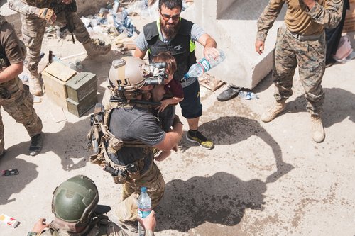 U.S. Airman carries a child at an Evacuee Control Checkpoint at Hamid Karzai International Airport, Kabul
