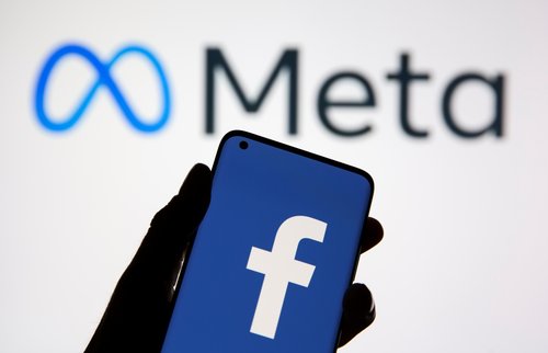 A smartphone with Facebook's logo is seen in front of displayed Facebook's new rebrand logo Meta in this illustration