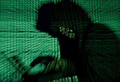 FILE PHOTO: Man holds laptop computer as cyber code is projected on him in this illustration picture
