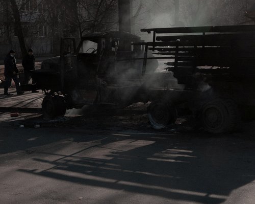 People walk past a burnt vehicle in Kyiv