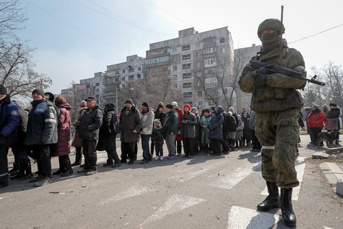 Local residents queue for humanitarian aid in the besieged southern port of Mariupol