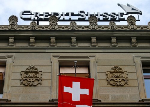 FILE PHOTO: Switzerland's national flag flies below a logo of Swiss bank Credit Suisse in Zurich