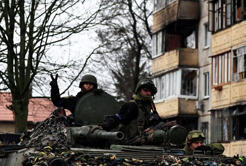 A Ukrainian army soldier flashes a victory sign as he stands in an armoured vehicle, amid Russia's invasion on Ukraine, in Bucha, in Kyiv region