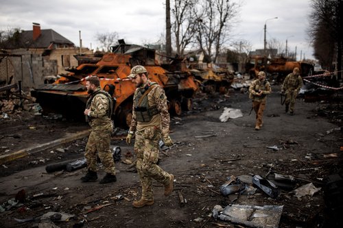 Ukrainian soldiers walk next to destroyed Russian tanks and armoured vehicles in Bucha
