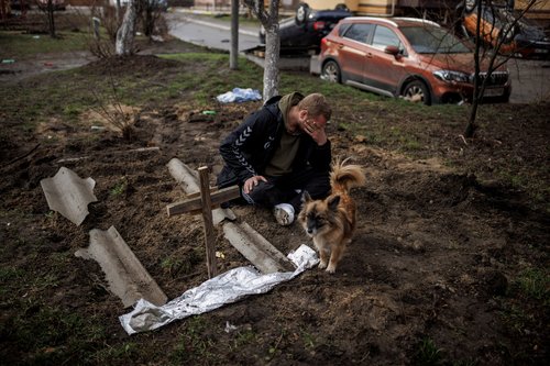 Serhii Lahovskyi mourns next to the grave of his friend Ihor Lytvynenko, in Bucha