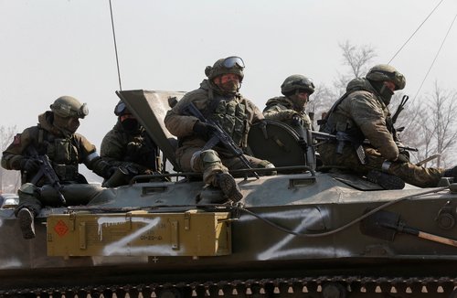 Service members of pro-Russian troops are seen atop of an armoured vehicle in the besieged city of Mariupol