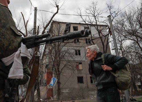 A service member of pro-Russian troops stops a civilian to check his documents in Mariupol
