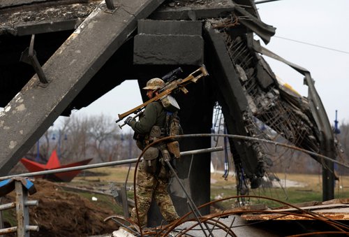 A service man carries his weapon as he walks under a damaged bridge, amid Russia's invasion of Ukraine, In Irpin