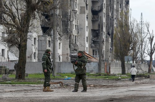 Service members of pro-Russian troops stand guard in a street in Mariupol