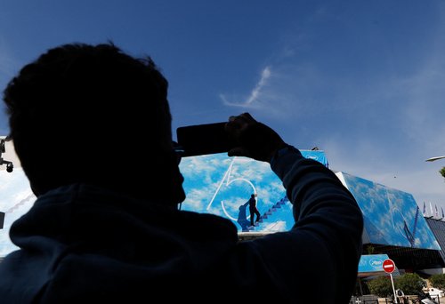 A man takes a photo of the official poster of the 75th Cannes Film Festival