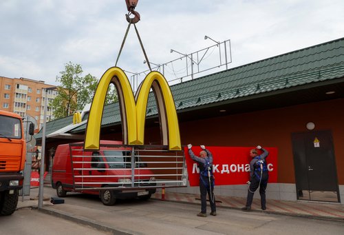 Workers remove the logo of McDonald's in Kingisepp