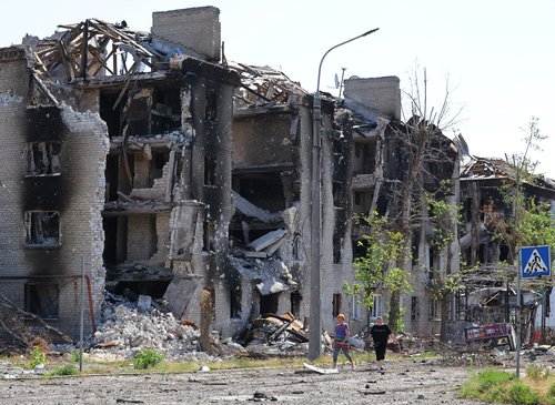 Local residents walk past destroyed apartment buildings in Sievierodonetsk