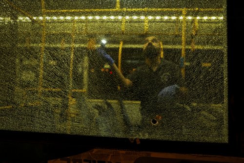 An Israeli security personal stands behind a shattered window of a bus as he checks it following an incident in Jerusalem
