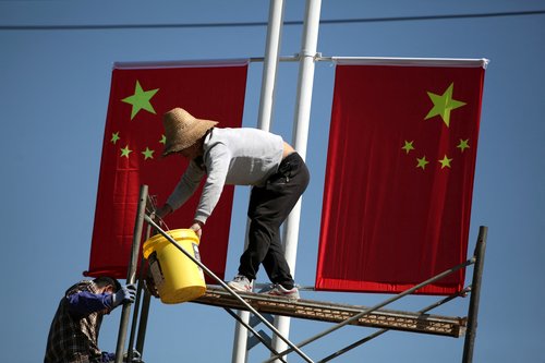 FILE PHOTO: Workers hang up Chinese flags on a street ahead of the 70th founding anniversary of People's Republic of China in Kunming, Yunnan