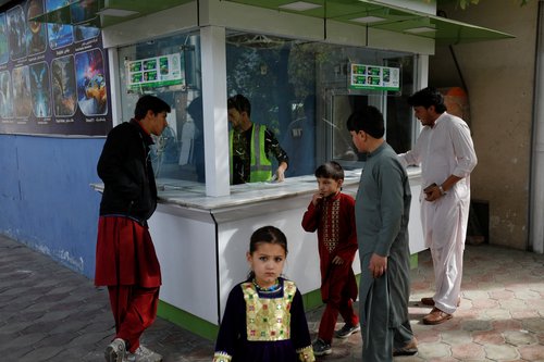 People stand next to a ticket booth in an amusement park in Kabul