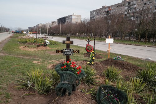FILE PHOTO: Graves of civilians killed during Ukraine-Russia conflict are seen next to apartment buildings in the southern port city of Mariupol