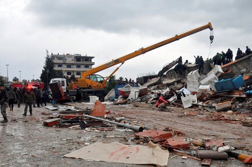 Rescuers search for survivors at a damaged site, following an earthquake, in Latakia