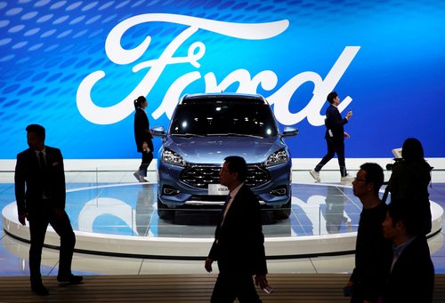 FILE PHOTO: People walk by a Ford Escape SUV displayed during the media day for the Shanghai auto show in Shanghai