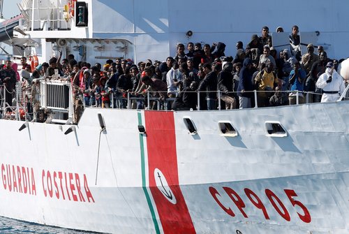 FILE PHOTO: Migrants arrive by the Italian coastguard vessel Peluso in the Sicilian harbour of Augusta