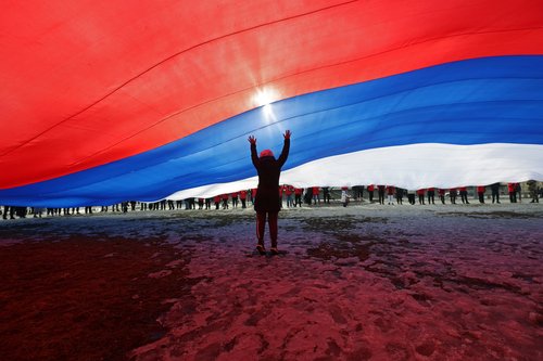 A participant stands under a giant Russian national flag during an event marking the ninth anniversary of Russia's annexation of Crimea, in Saint Petersburg