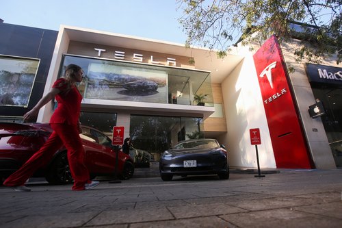 A woman walks by a Tesla dealership in Mexico City