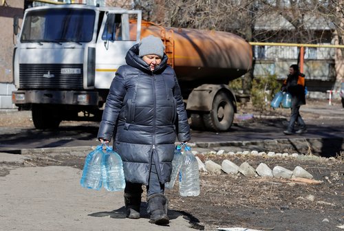A local resident carries bottles with water in Zolote