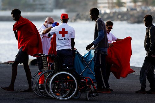Migrants walk towards a Red Cross tent after disembarking from a Spanish coast guard vessel in the port of Arguineguin