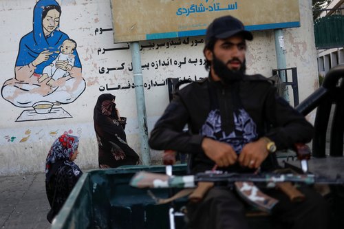 An Afghan woman and a girl walk in a street in Kabul