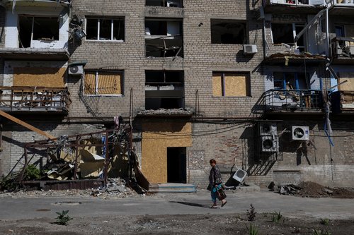Woman walks past a residential building damaged by a Russian military strike in Pokrovsk