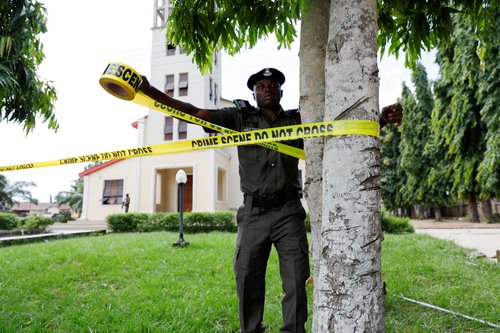 FILE PHOTO: A police officer ties a crime scene tape following an attack on worshippers by gunmen at St. Francis Catholic Church in Owo