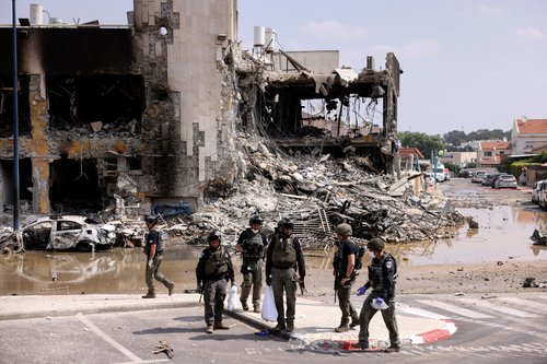 Israeli security gather near a rifle at the site of a battle following a mass infiltration by Hamas gunmen from the Gaza Strip, in Sderot