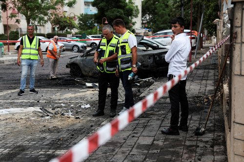 People attend the site of where a rocket landed after being launched towards Israel from the Gaza Strip, in Ashdod, southern Israel