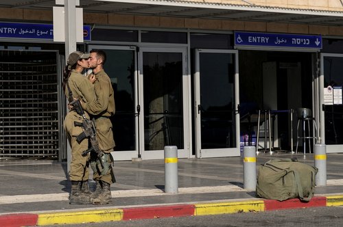 Israeli soldiers kiss by a train station, amid the ongoing conflict between Israel and the Palestinian Islamist group Hamas, in Ashkelon