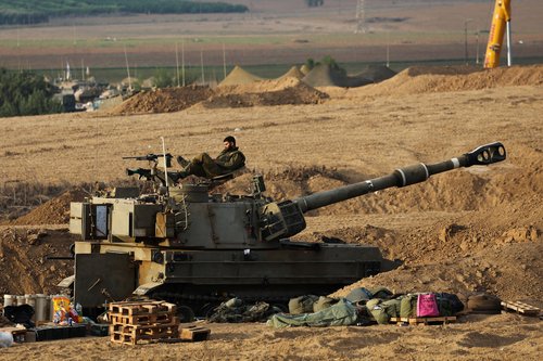Israeli sits on self-propelled howitzer during the early morning near Israel's border with the Gaza Strip