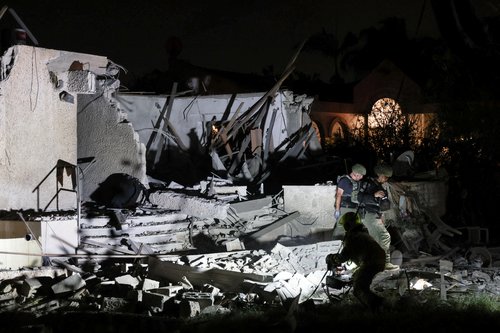 Israeli security officials work at the scene of a home that was struck and damaged by a rocket that was fired from the Gaza Strip towards central Israel