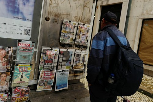 A man looks at the newspaper's front pages, in Lisbon