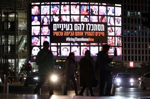 A screen displays photos of people who were abducted by Hamas gunmen during the October 7 attack on Israel, in Tel Aviv