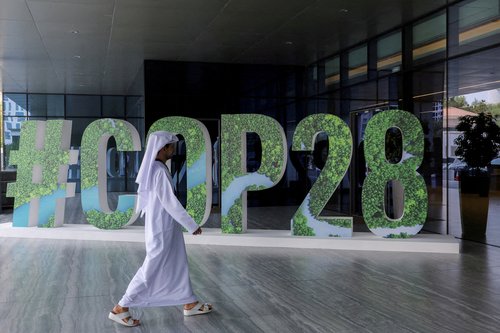 FILE PHOTO: A person walks past a "#COP28" sign during The Changemaker Majlis, a one-day CEO-level thought leadership workshop focused on climate action, in Abu Dhabi
