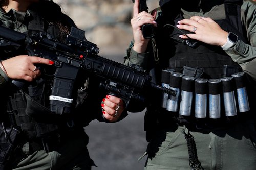 An Israeli soldier holds a weapon as Muslim Palestinians hold Friday prayers, amid a temporary truce in Gaza between Hamas and Israel, in Jerusalem