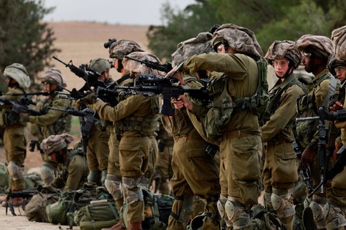 Israeli soldiers gather on the Israeli side of the Israel-Gaza border, amid the ongoing conflict between Israel and the Palestinian Islamist group Hamas, as seen from southern Israel