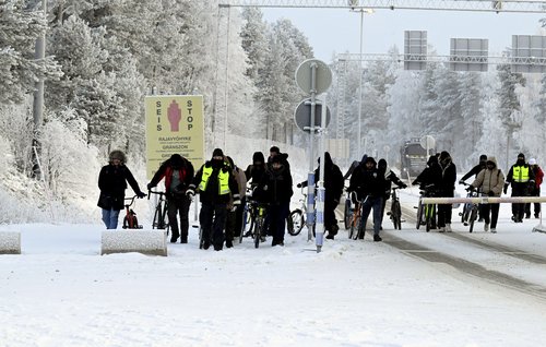 Migrants walk at the border crossing between Finland and Russia, in Finnish Lapland