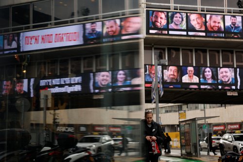 A woman walks past screens displaying pictures of hostages kidnapped in the deadly October 7 attack on Israel by Hamas, in Tel Aviv