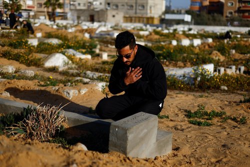 Palestinian man Ibrahim Hassouna, who lost his family during Israel's military offensive, prays at a grave during the holy month of Ramadan, in Rafah, in the southern Gaza Strip