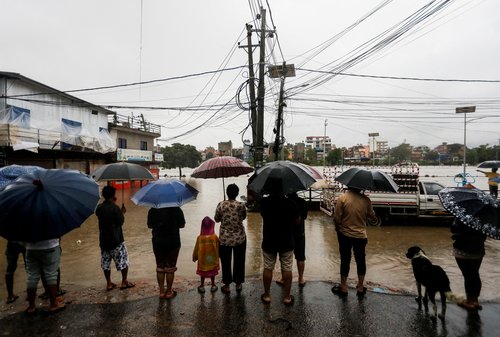 People look towards a flooded area along the bank of overflowing Bagmati River following heavy rains in Kathmandu